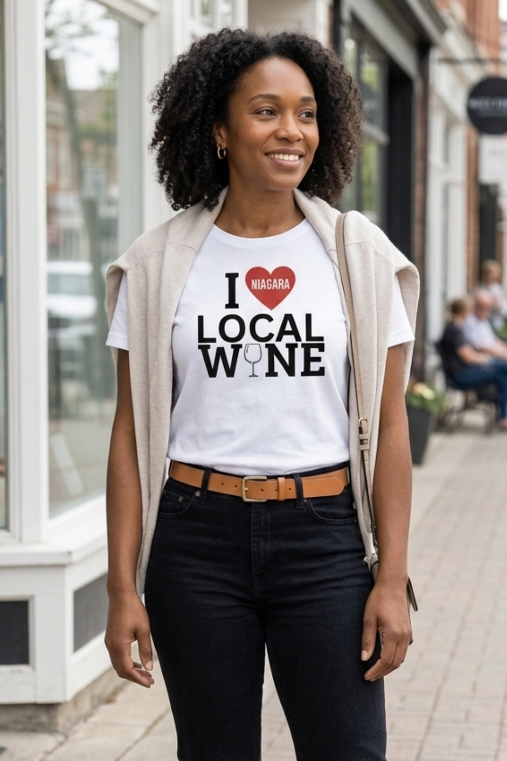 Woman wearing a white I Love Niagara Local Wine t-shirt with red heart and wine glass design, styled with black jeans while shopping in Niagara-on-the-Lake.