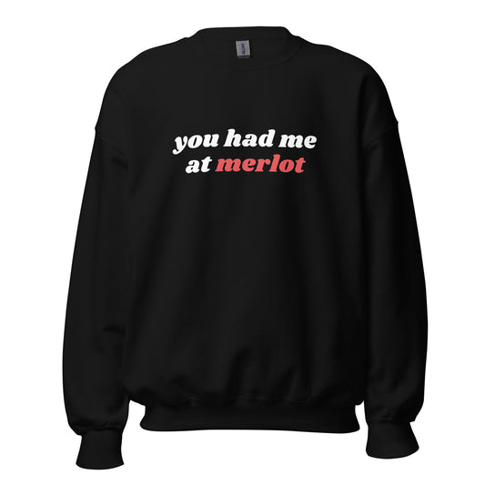 Product mockup of a Black crewneck wine sweatshirt featuring “You Had Me at Merlot” in bold white and red retro-style lettering, with long sleeves, ribbed cuffs and a relaxed unisex fit.